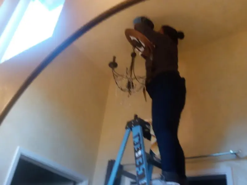 Electrician installing a chandelier in a Grand Forks residence